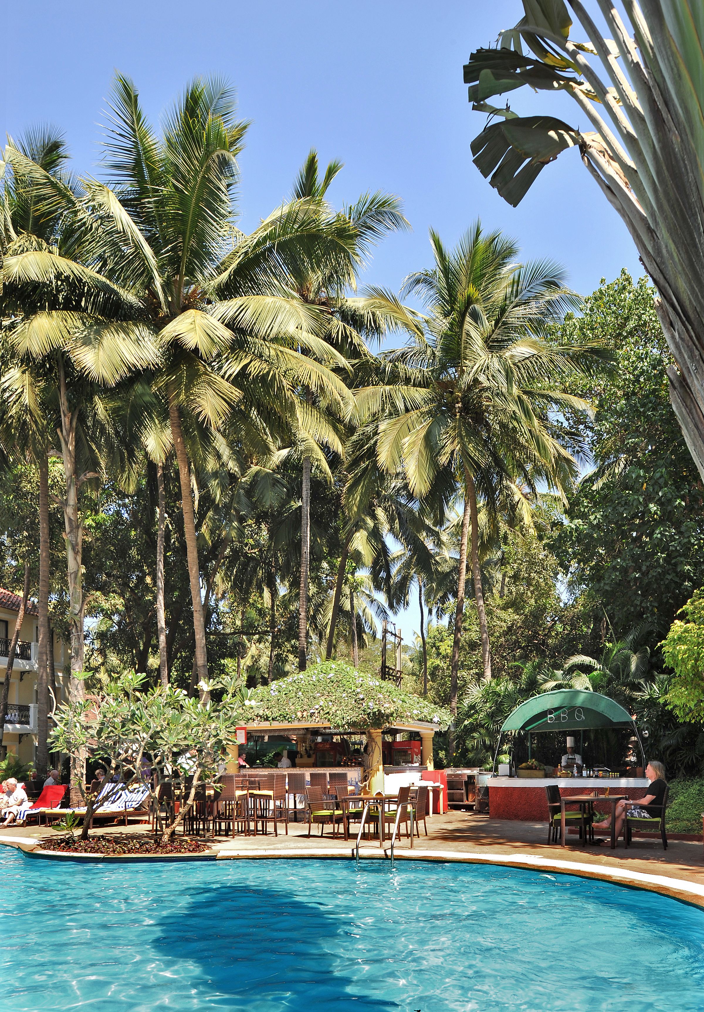 A poolside area with palm trees, outdoor seating, and a bar area.