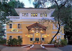 Un hotel con una entrada destacada, un patio cubierto y numerosas plantas en macetas.