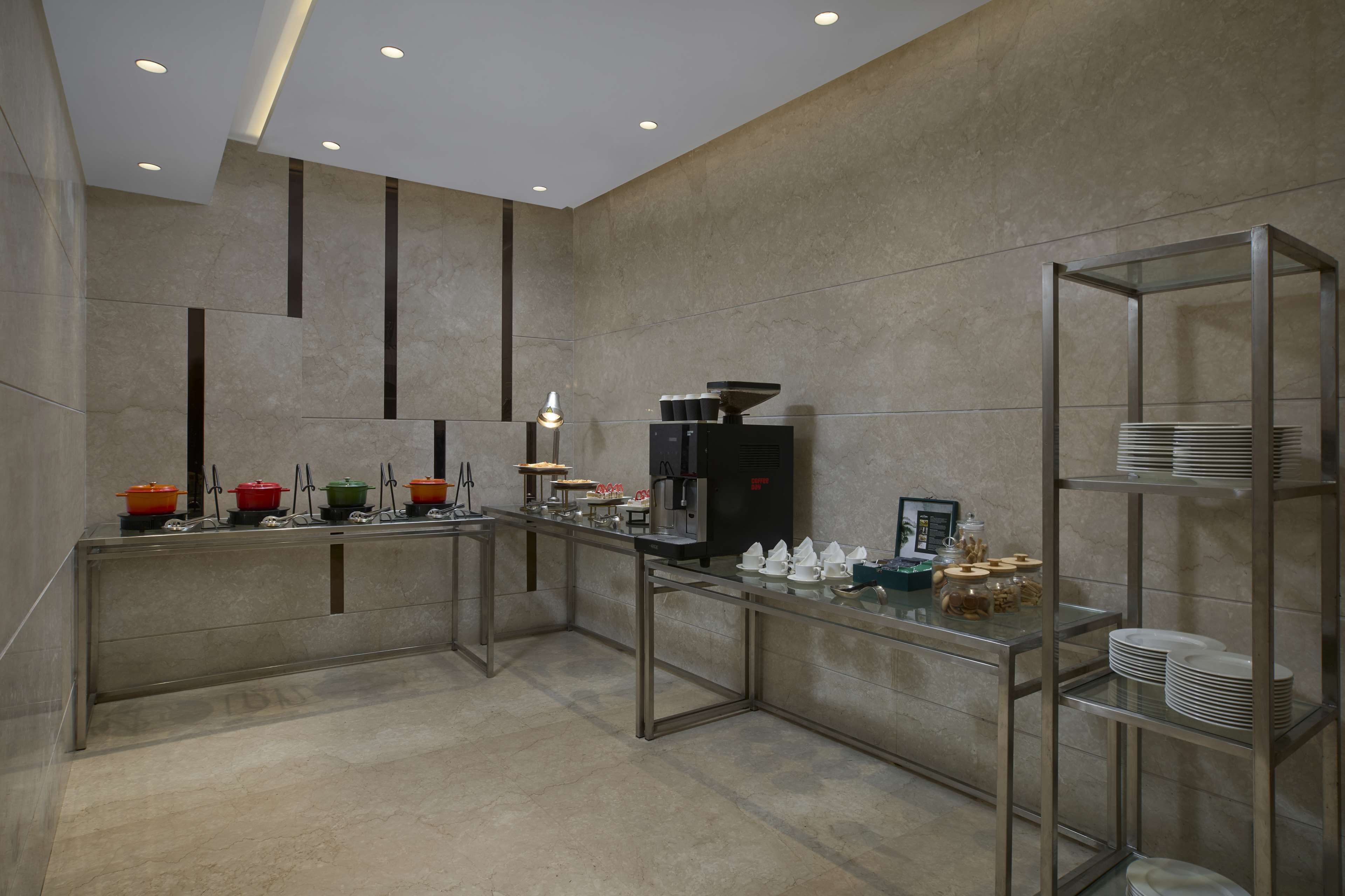 A modern kitchen with stainless steel appliances, a coffee machine, and a glass display case with utensils.