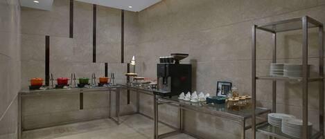 A modern kitchen with stainless steel appliances, a coffee machine, and a glass display case with utensils.