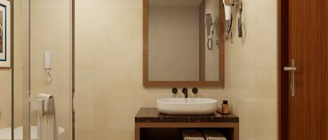 Un baño con un espejo grande, un lavabo, un perchero para toallas y una zona de ducha.