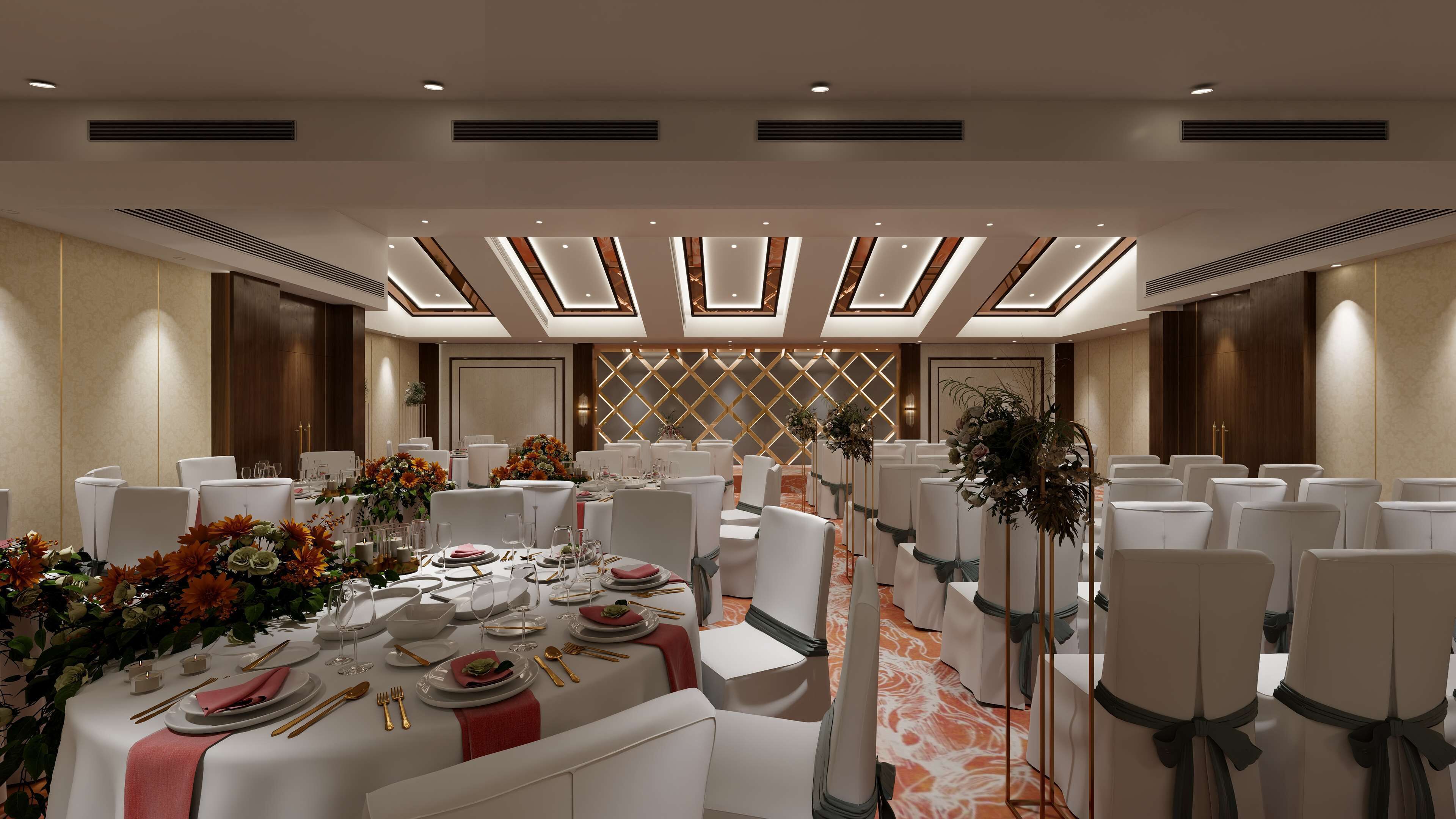 Un salón de banquetes con mesas redondas, sillas blancas y centros de mesa florales.