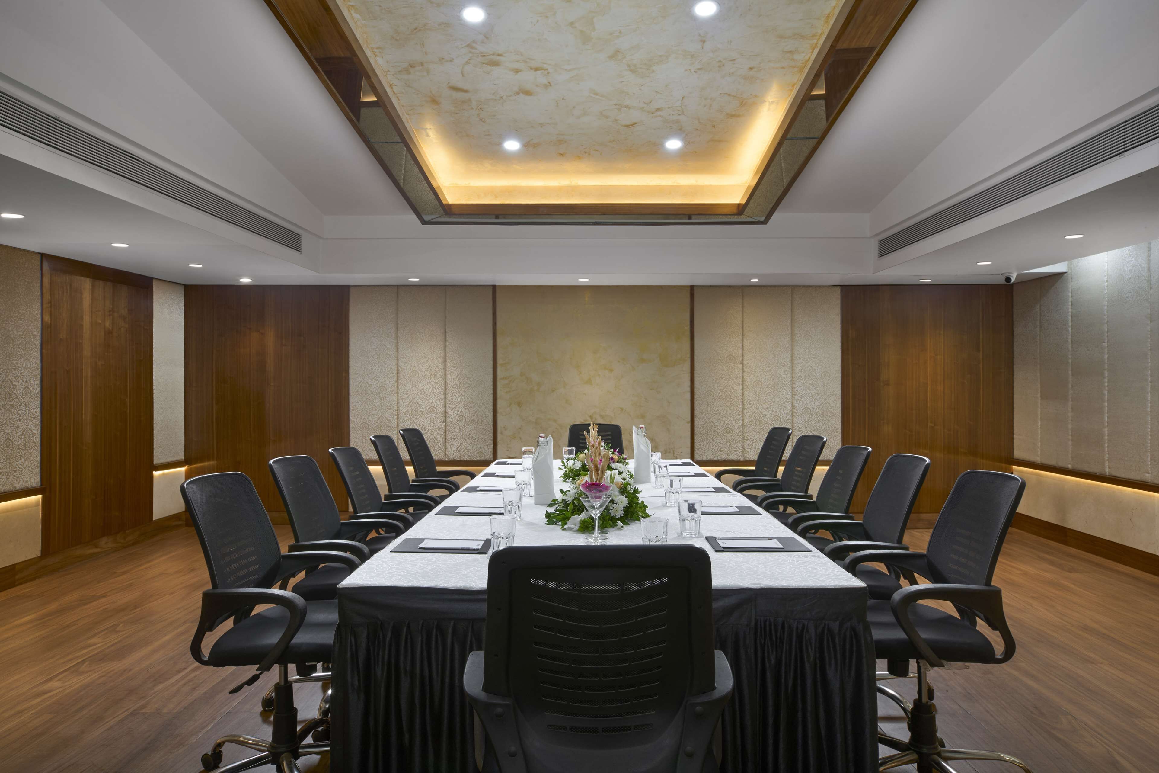 A conference room with a long table, chairs, and a floral centerpiece.