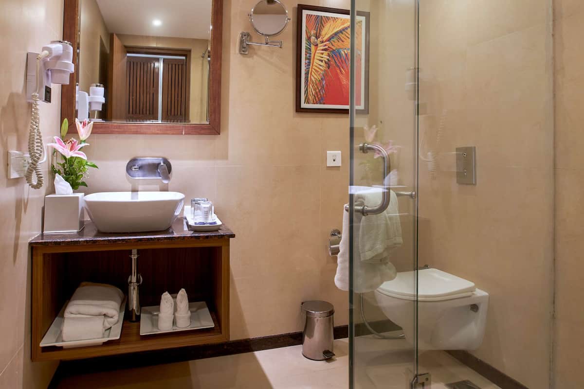 A modern bathroom with a glass-enclosed shower, a sink with a mirror above it, and a toilet.