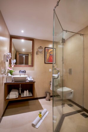 A modern bathroom with a glass-enclosed shower, a sink with a mirror above it, and a toilet. - Park Inn by Radisson Goa Candolim (Candolim)