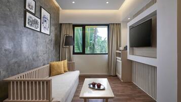 Una habitación de hotel moderna con sofá, una mesita de centro, un televisor de pantalla plana y cuadros en la pared.
