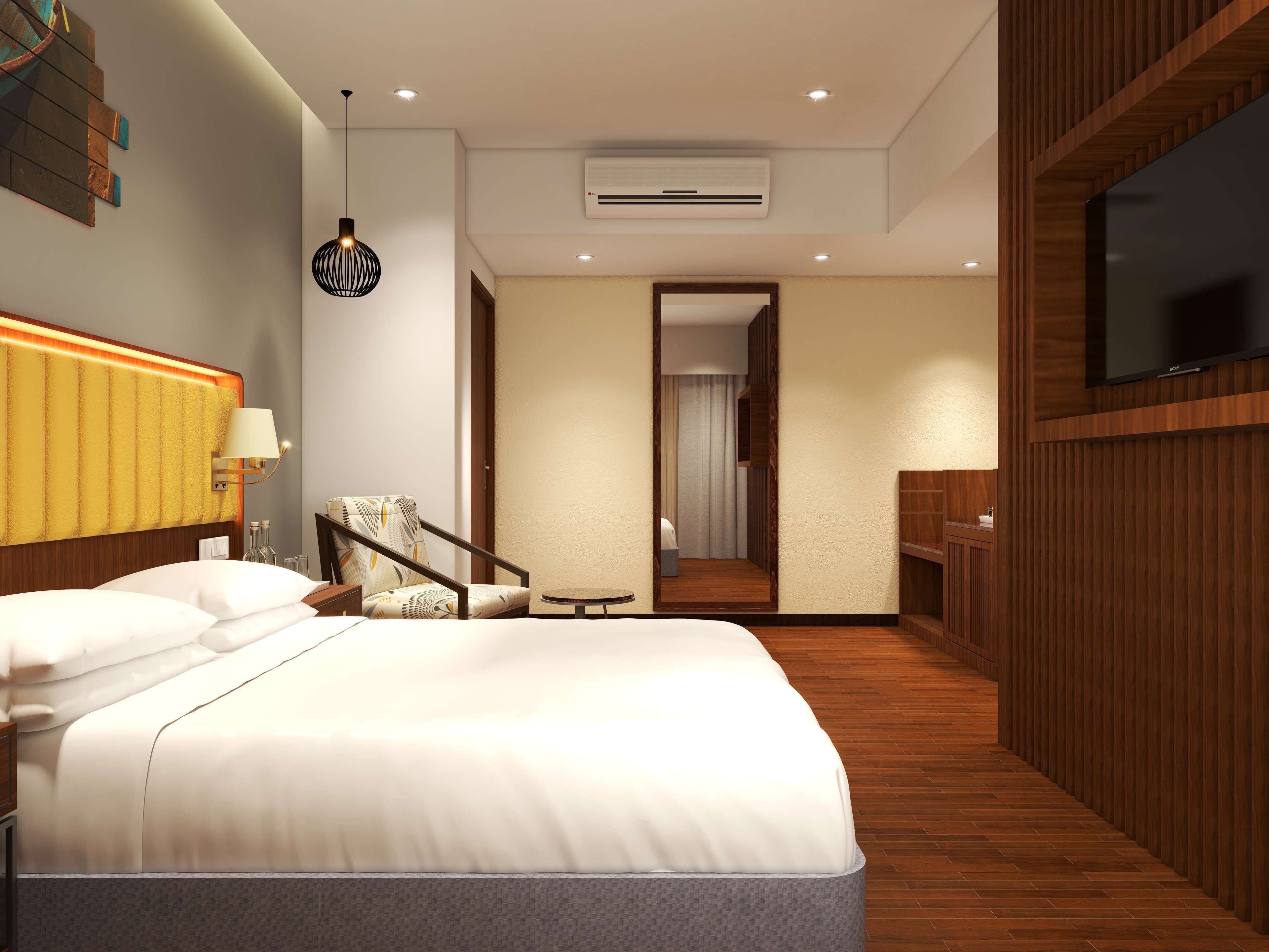 A modern hotel room with a large bed, a chair, a small table, and a TV mounted on the wall.