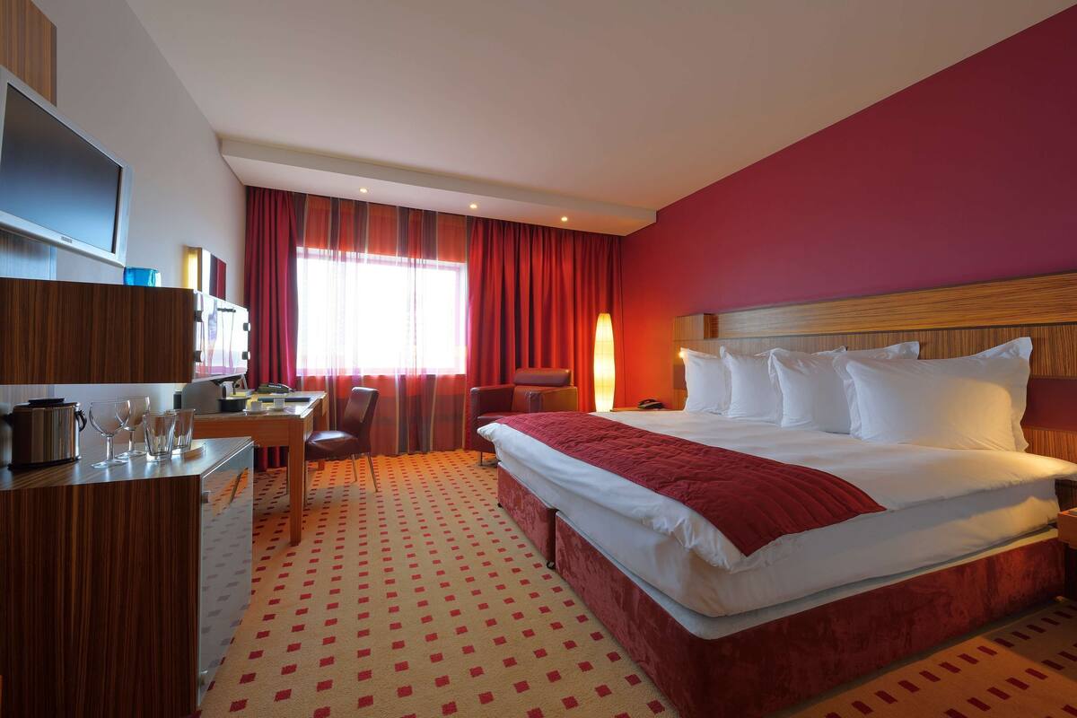 A hotel room with a bed, desk, chair, and a television.