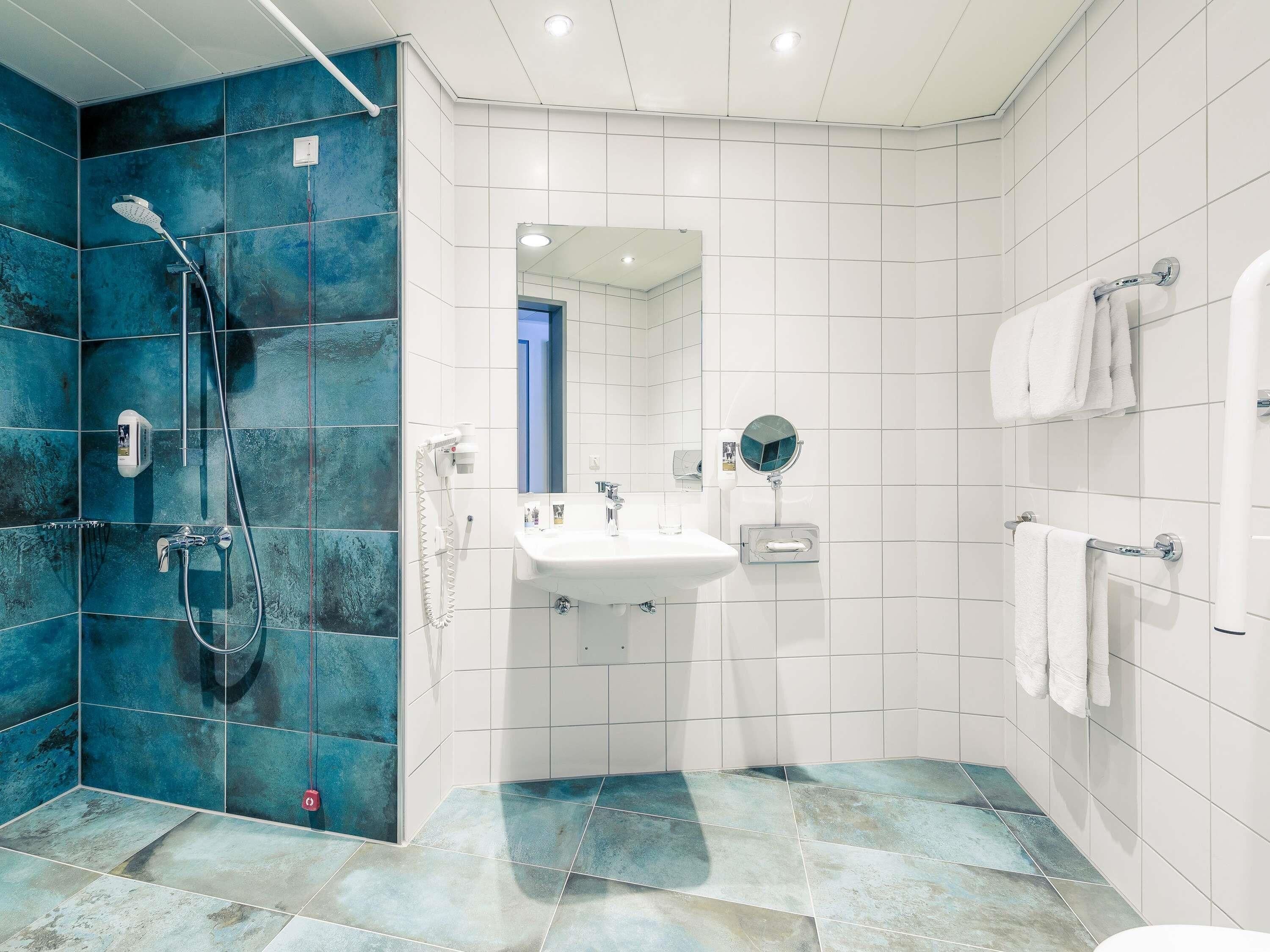 Ein modernes Badezimmer mit Dusche, Waschbecken und Spiegel.