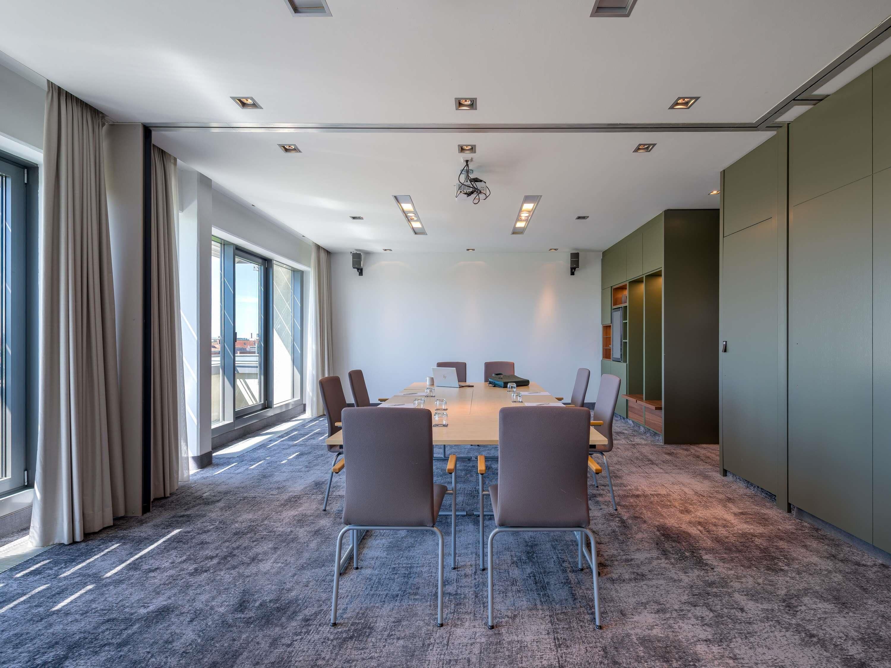 A conference room with a long table, chairs, and a large window.