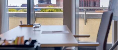 A conference room with a large window, a desk, and a chair.