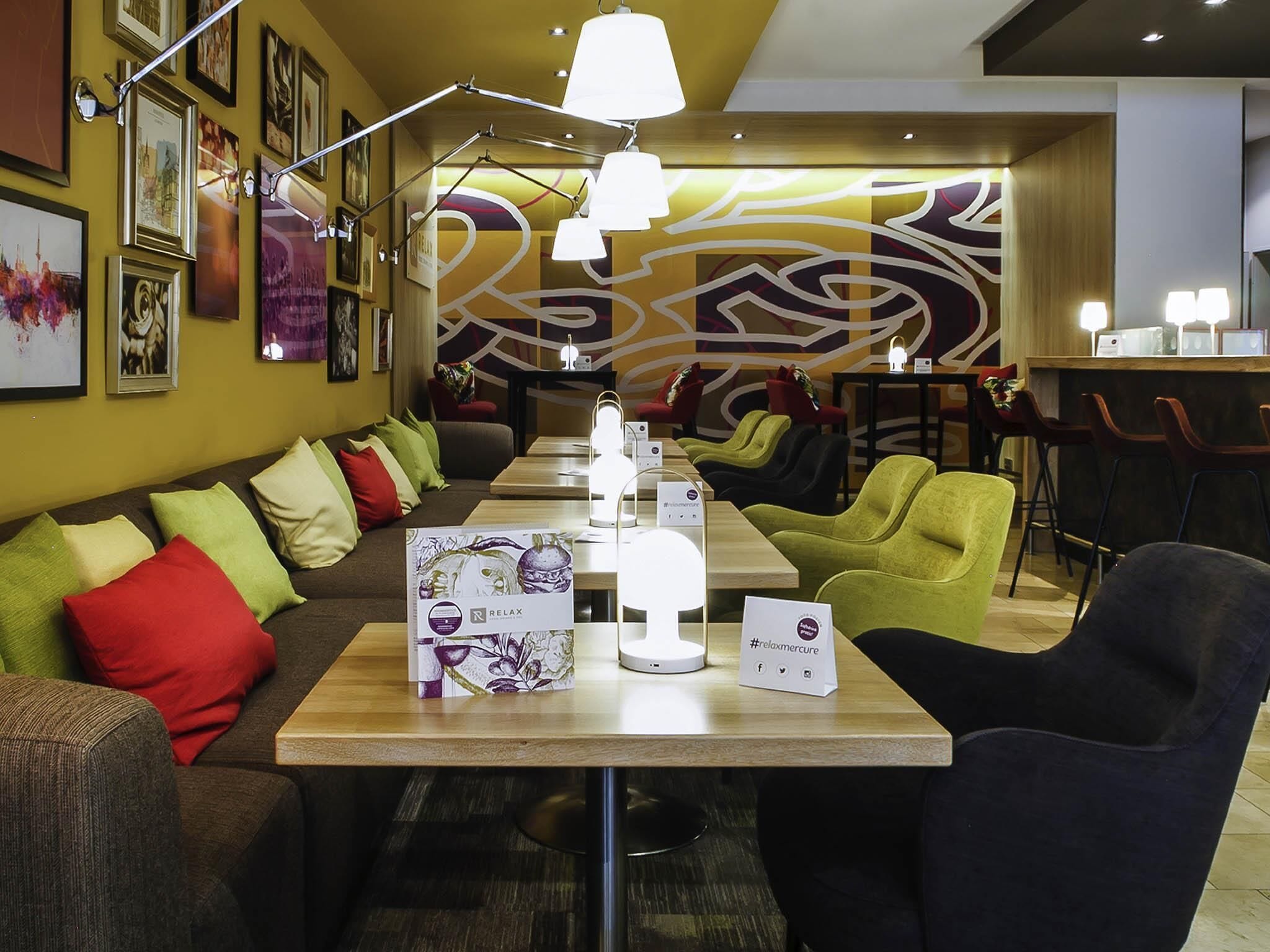 A modern lounge area with a sofa, chairs, and a table with a massage chair.