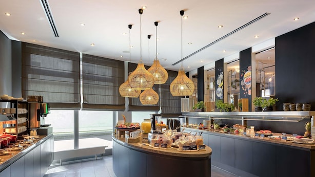 A modern kitchen with a central island, overhead lighting, and a buffet setup. - Mercure Hotel Hannover Mitte (Hannover)