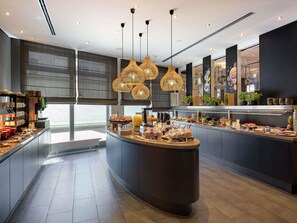 Una cocina moderna con una isla central, iluminación colgante y una disposición tipo bufé.