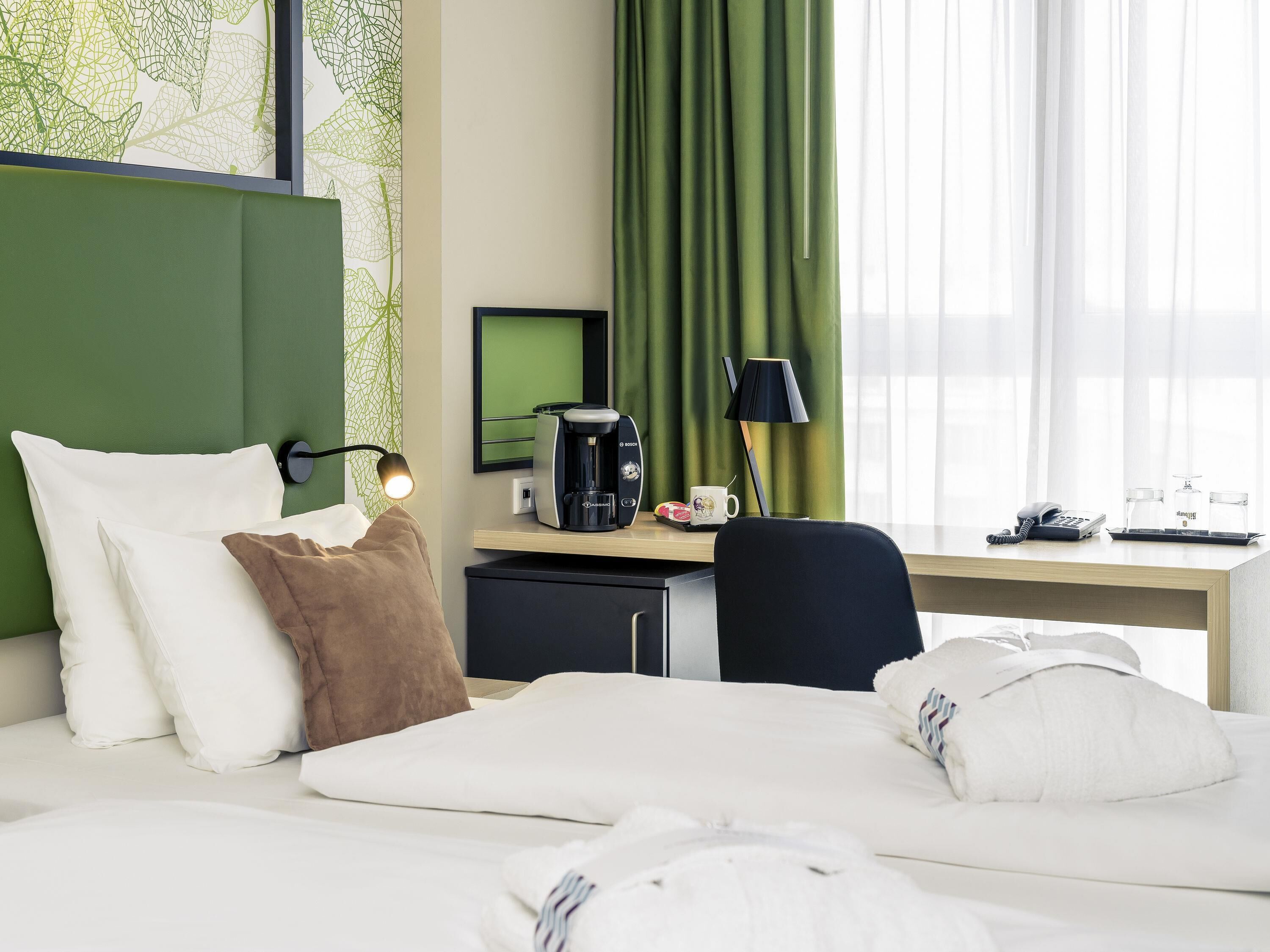 Hotellihuone, jossa on sänky, työpöytä, kahvinkeitin, lamppu ja puhelin.