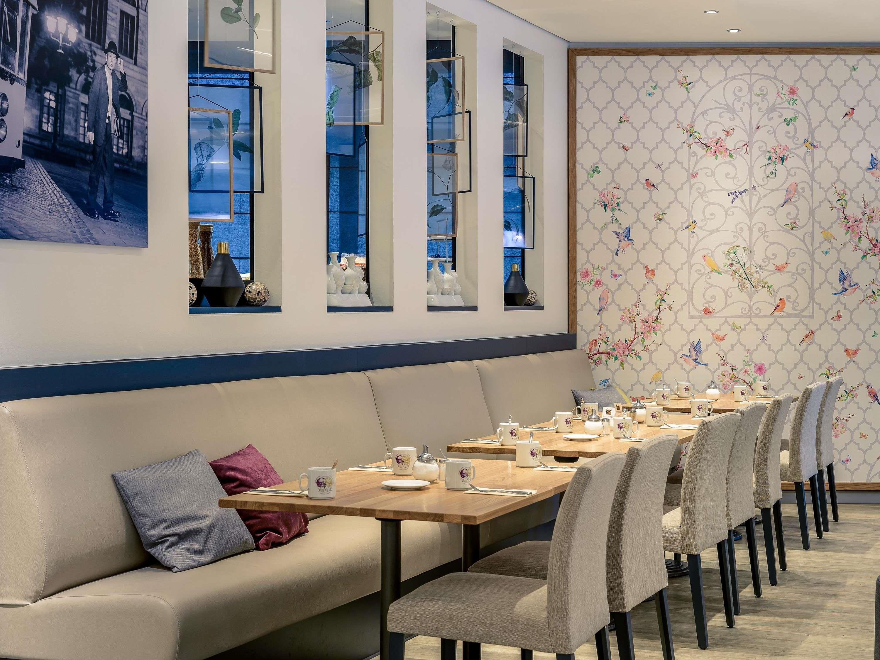 A dining area with a long table, chairs, and a sofa with cushions.