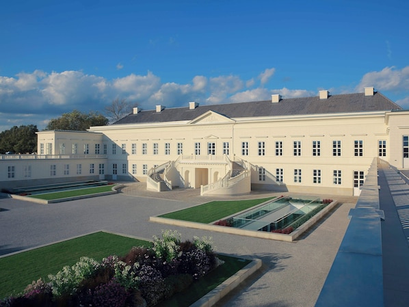 A large, symmetrical building with a central staircase and a formal garden.