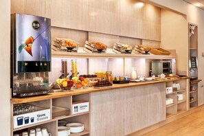A buffet setup with various food items and a coffee machine.