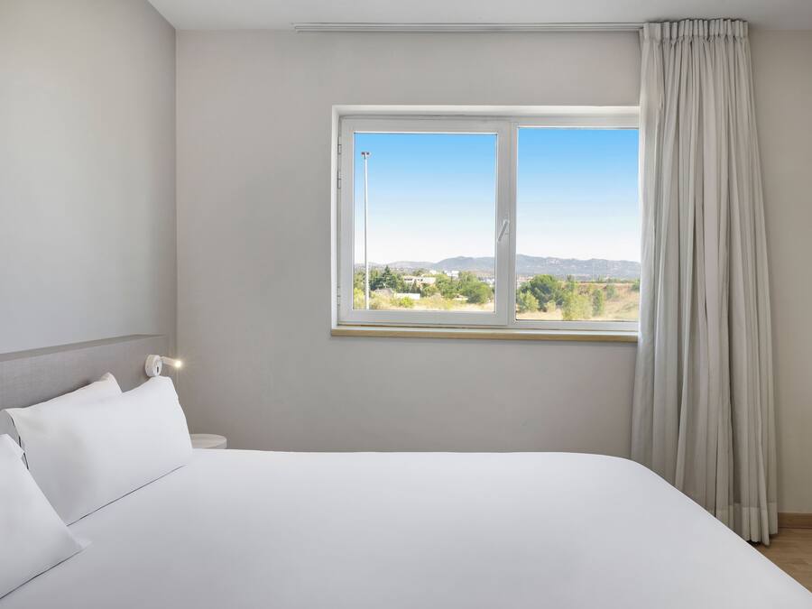 Un dormitorio con una cama grande, una ventana con vistas al exterior y una cortina.