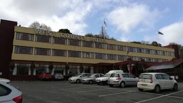 A West County Hotel with a parking lot and several cars parked in front.