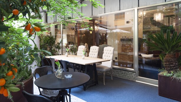 Un comedor moderno en interior con una mesa redonda y sillas, rodeado de paredes de vidrio y plantas en macetas.