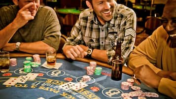 A casino table with playing cards, poker chips, and a bottle.