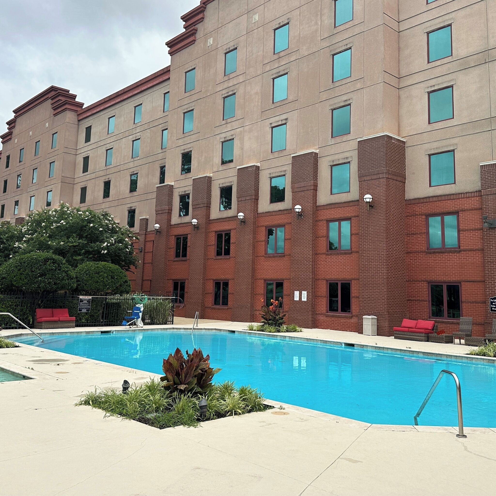 A hotel with a swimming pool, red brick exterior, and multiple windows.