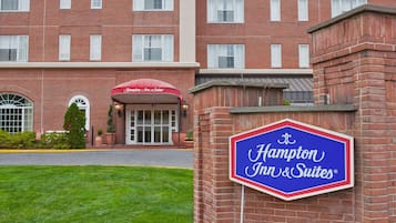 Un hôtel Hampton Inn & Suites à la façade en briques, doté de grandes fenêtres et d’une pelouse bien entretenue.