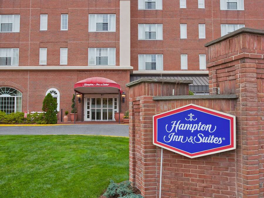 Un hôtel Hampton Inn & Suites à la façade en briques, doté de grandes fenêtres et d’une pelouse bien entretenue.