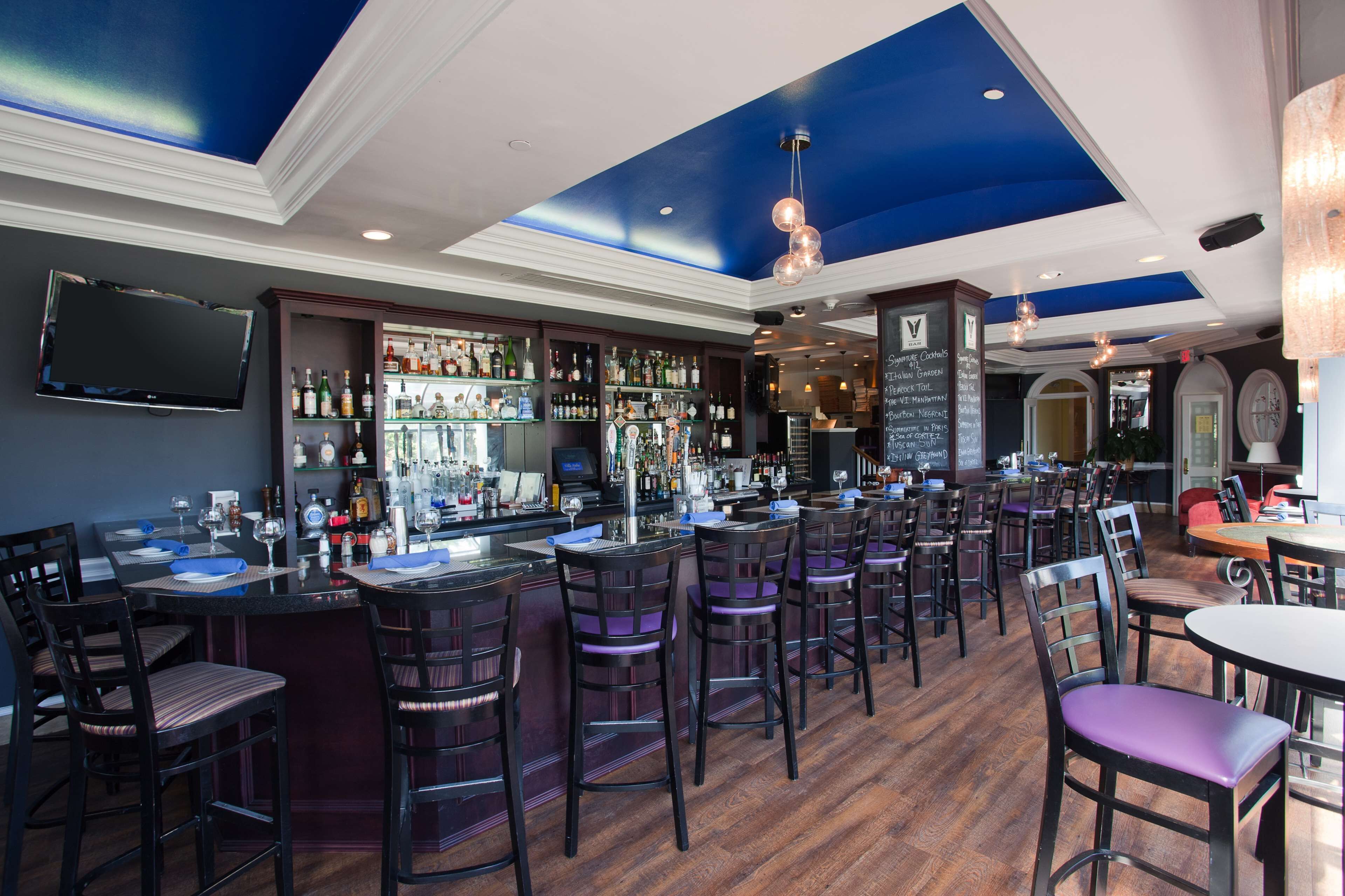 A bar area with multiple seating options, a bar counter, and a variety of bottles and glasses.