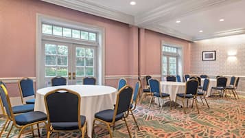 A conference room with round tables and blue chairs, large windows, and patterned carpet.