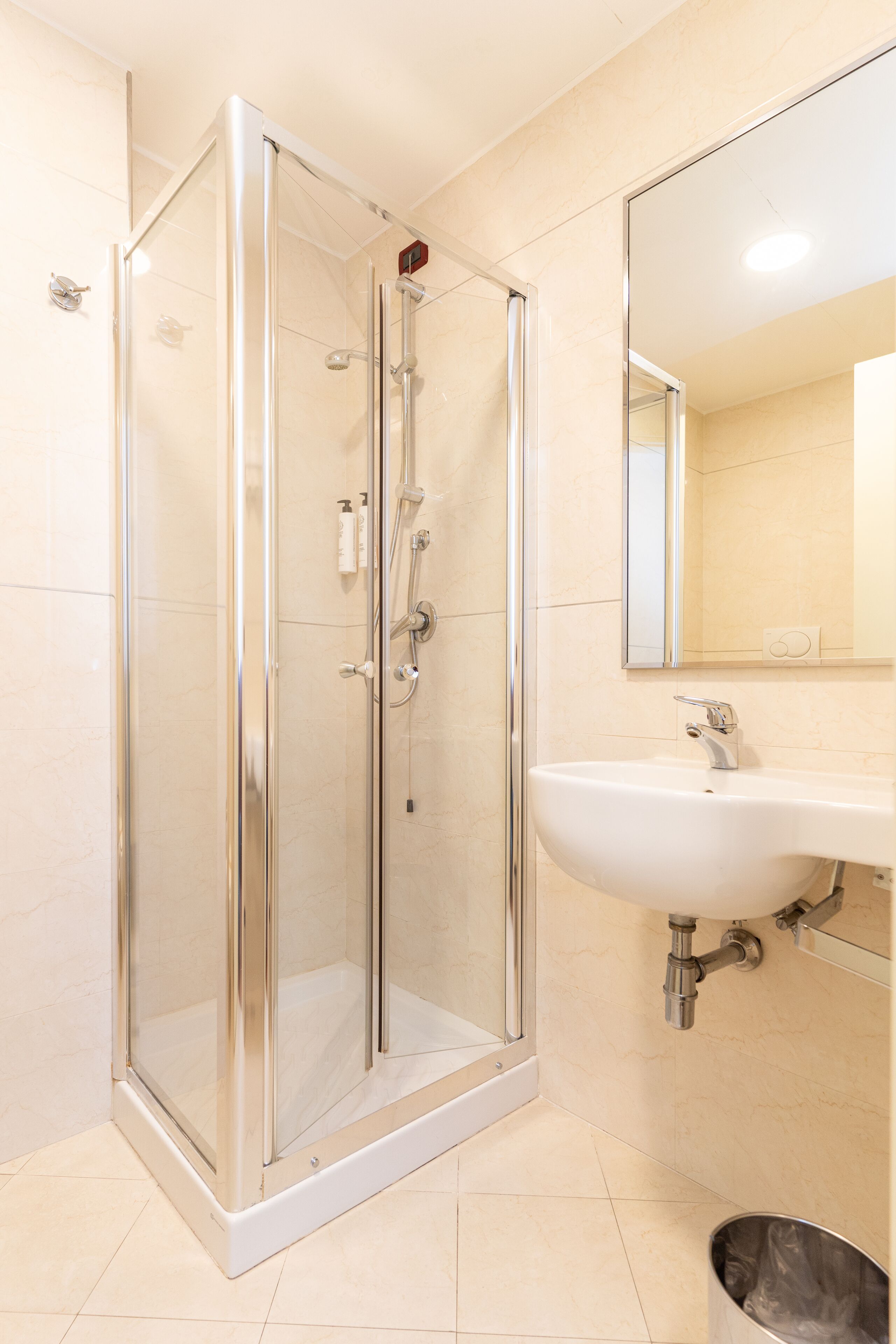 Un bagno moderno con doccia a vetro, lavabo bianco e specchio sopra il lavello.
