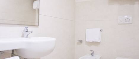 A bathroom with a sink, bidet, and toilet.
