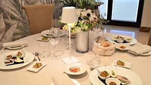 A round dining table set for a meal with various dishes, glasses, and a vase of flowers. - Hotel Europa (Rende)