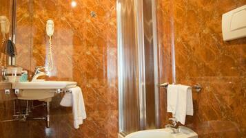 A bathroom with a marble floor, a sink, a bidet, a toilet, and a shower.