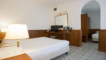 A hotel room with a bed, desk, chair, TV, and a mirror.
