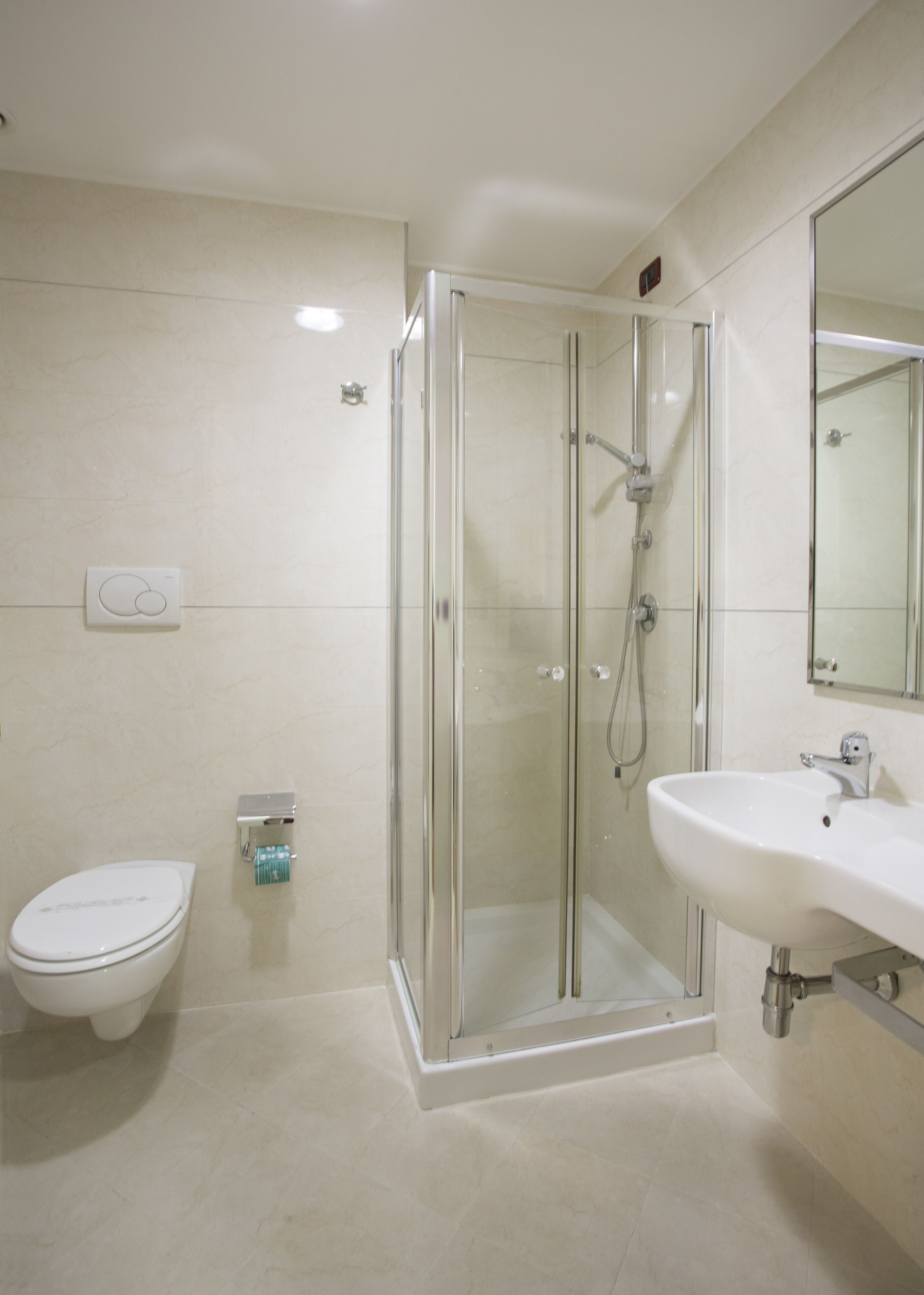 A modern bathroom with a glass-enclosed shower, a white toilet, and a sink with a mirror above it.
