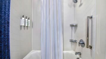 A modern bathroom with a freestanding bathtub, a showerhead, and a handrail.