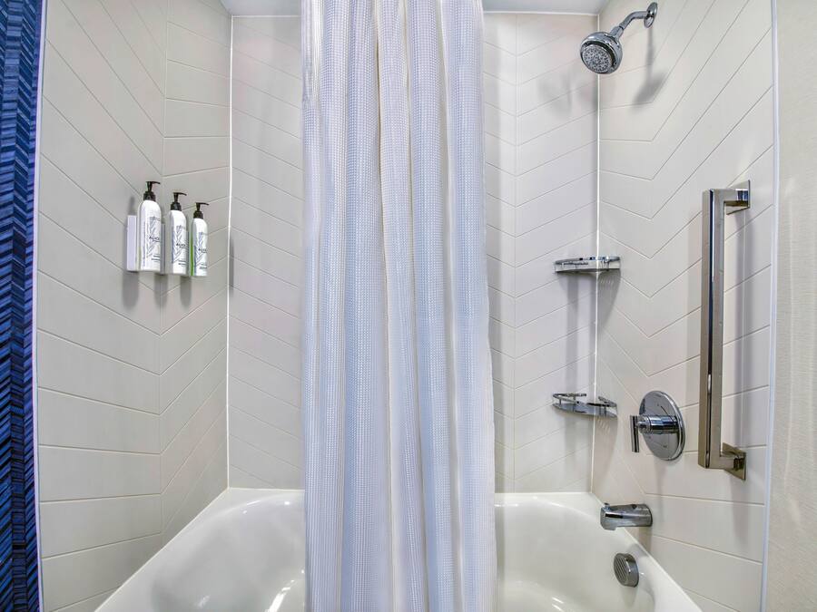 A modern bathroom with a freestanding bathtub, a showerhead, and a handrail.