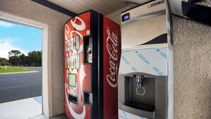 En försäljningsautomat med Coca-Colas logotyp och en Maxx Ice-kylare i en kommersiell miljö.