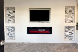Una sala de estar moderna con chimenea, televisor de pantalla plana y paneles de piedra decorativos.
