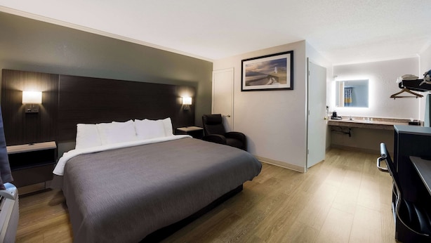 Ett hotellrum med en stor säng, ett skrivbord, en stol och ett litet pentry.