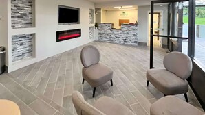 Ett välkomstområde med en vägg av natursten, en platt-TV och en öppen spis.