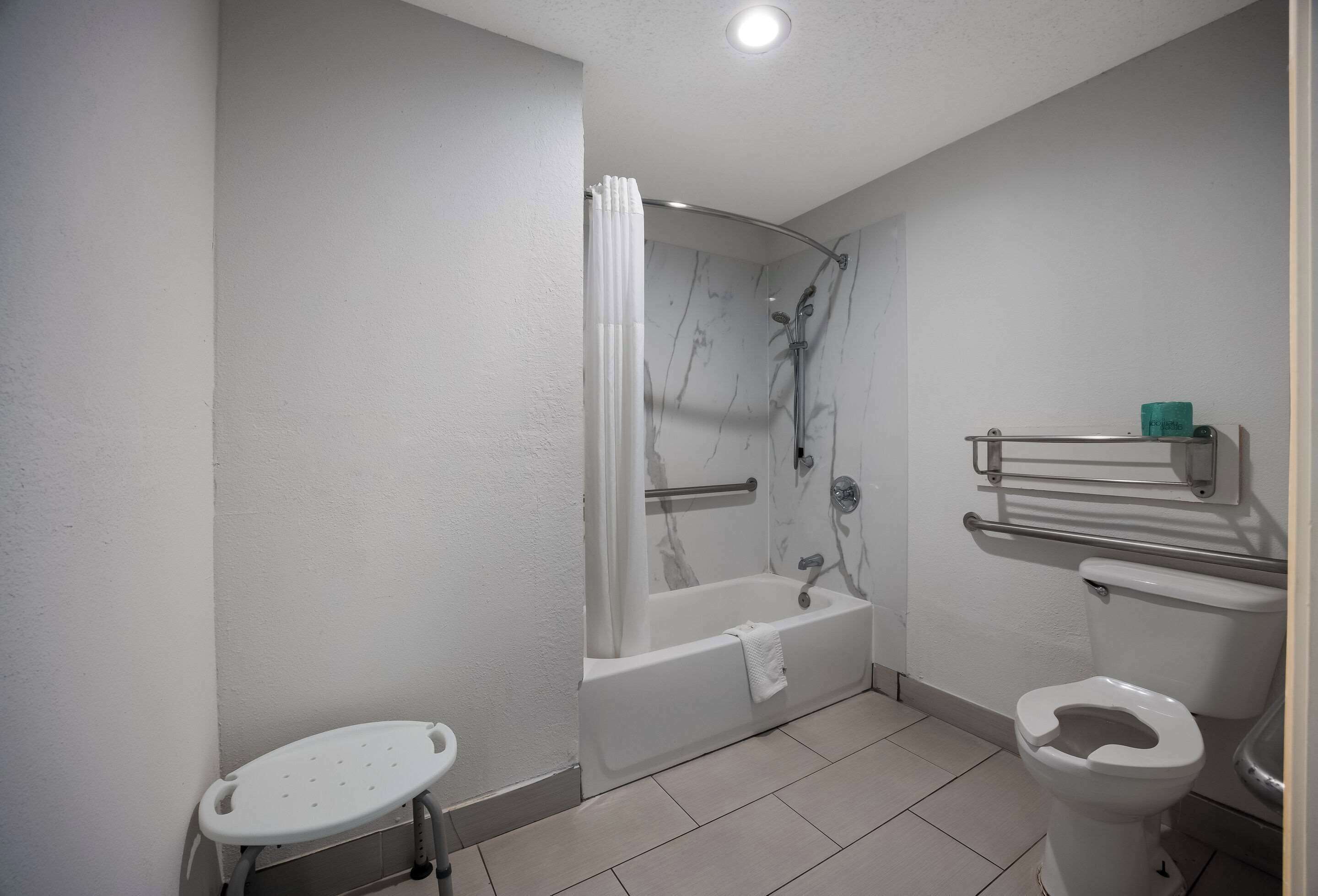 A bathroom with a bathtub, toilet, and a small stool.