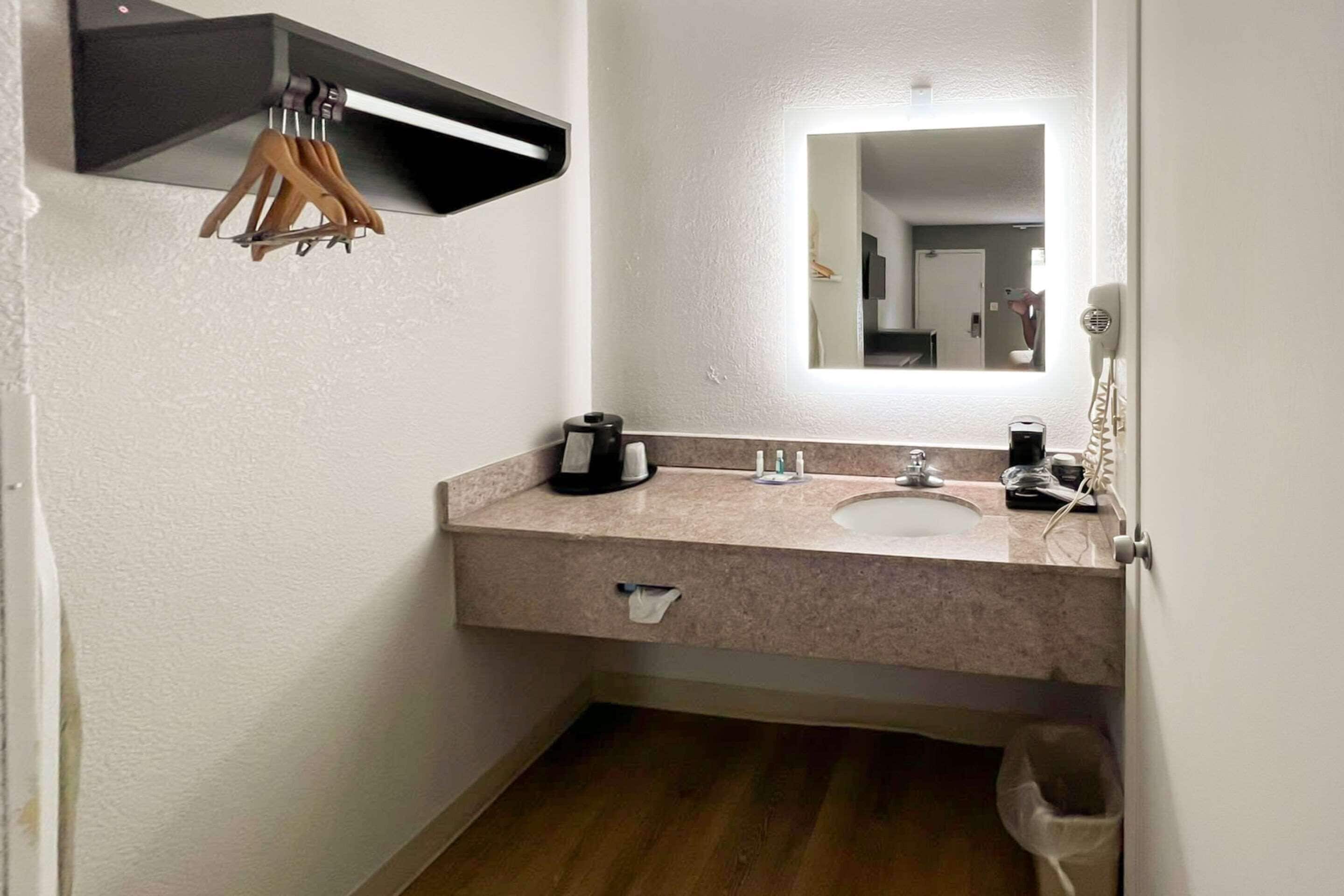 A bathroom with a sink, mirror, towel rack, and a trash bin.