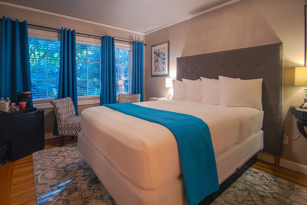 A hotel room with a large bed, a desk, and a chair.