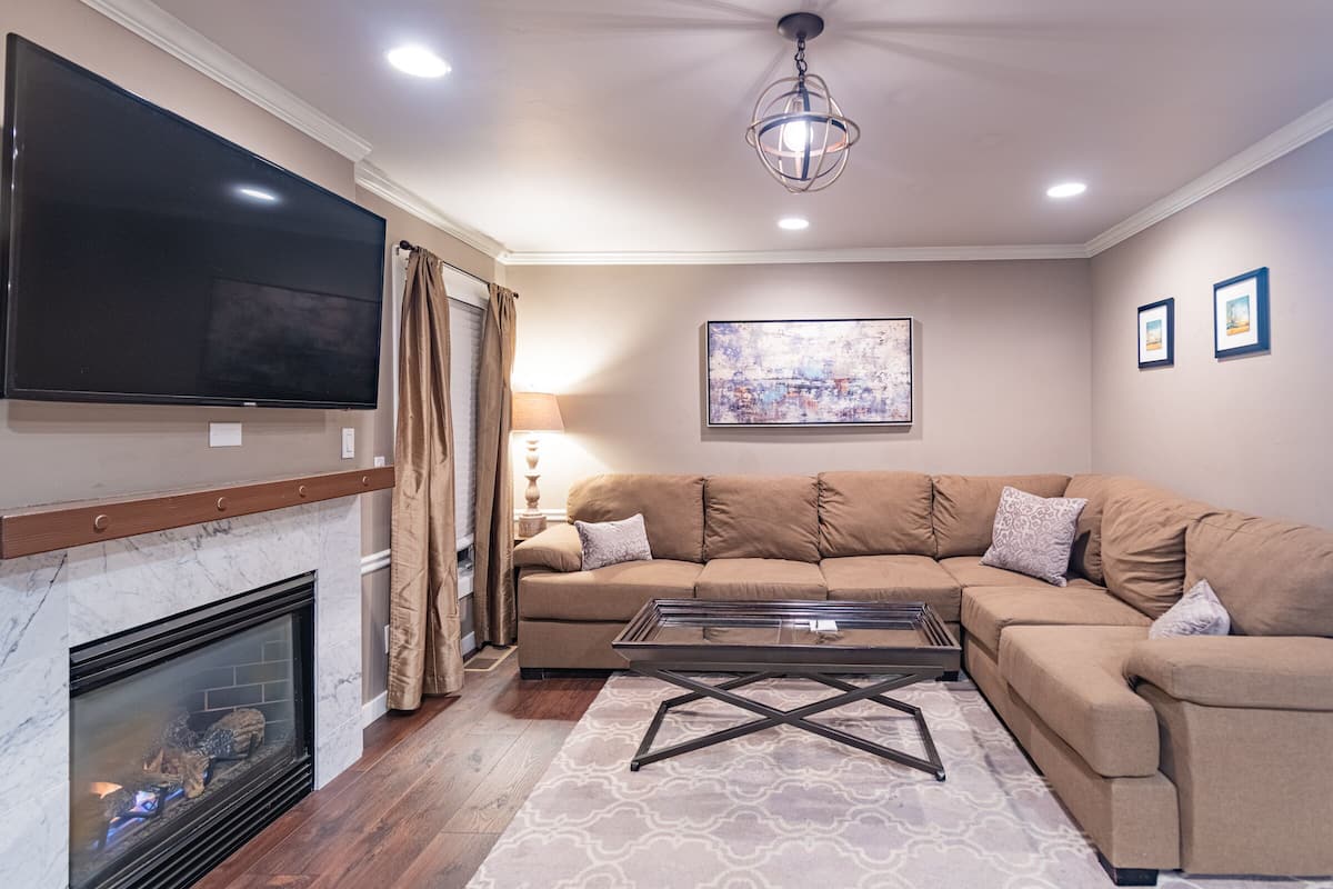 A living room with a fireplace, a large flat-screen TV, a sofa, and a coffee table.