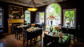 A dining area with tables and chairs, a chandelier, and large windows with views of greenery. - Inn & Spa at Parkside (Sacramento)