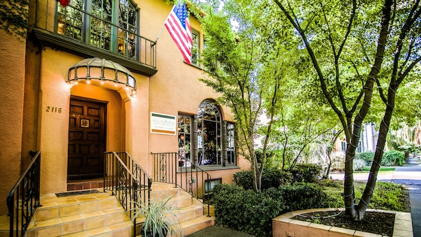 A building with a brown door, a sign, and an American flag. - Inn & Spa at Parkside (Sacramento)
