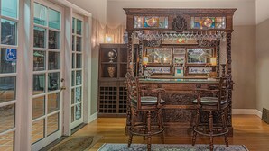 A bar area with two stools, a wooden cabinet with glass doors, and hanging light fixtures. - Inn & Spa at Parkside (Sacramento)